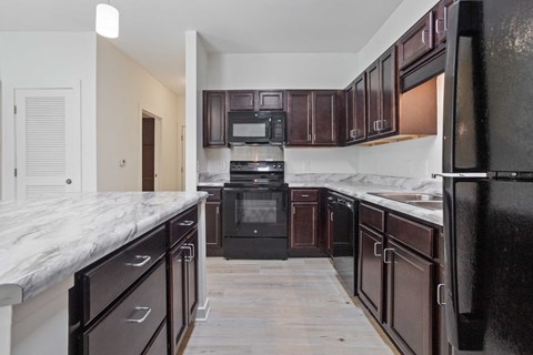 a kitchen with dark wood cabinets and marble counter tops