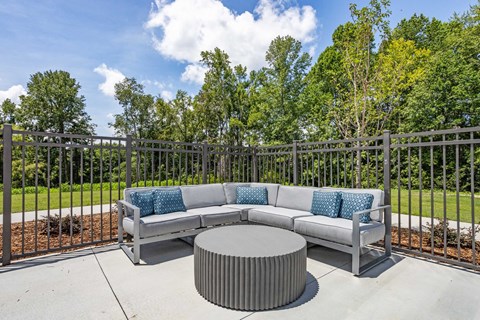 a patio with couches and a table in front of a fence