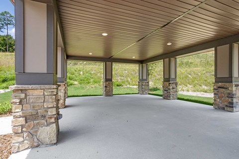 a covered parking area with stone pillars and a metal roof