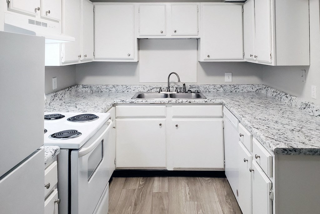 a kitchen with white cabinets and white appliances and wood-style flooring at Woodland Villas Apartments, Jasper