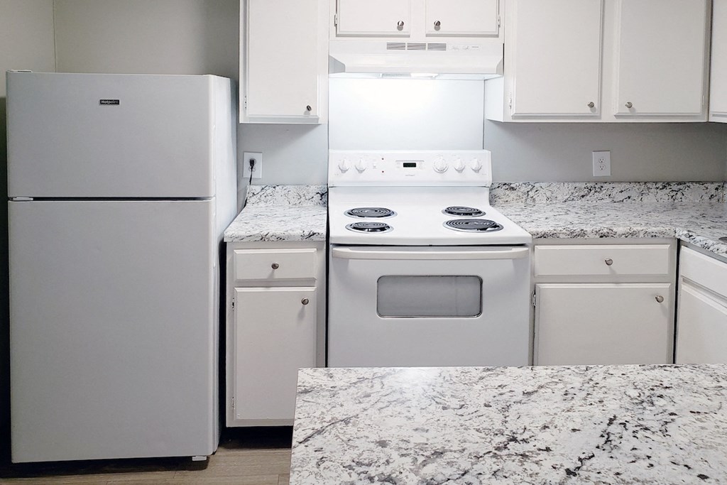 a kitchen with white appliances, white cabinets, and granite-inspired countertops at Woodland Villas Apartments, Jasper Alabama