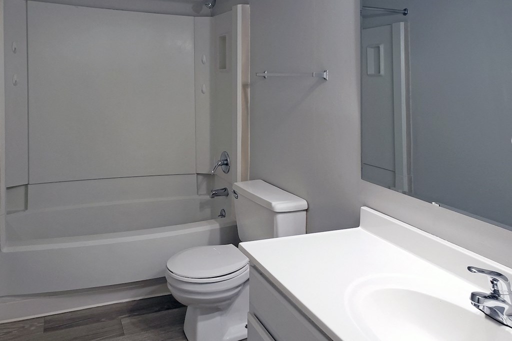 bathroom with large sink vanity and mirror, wood-style flooring and toilet, shower/tub at Woodland Villas Apartments, Alabama
