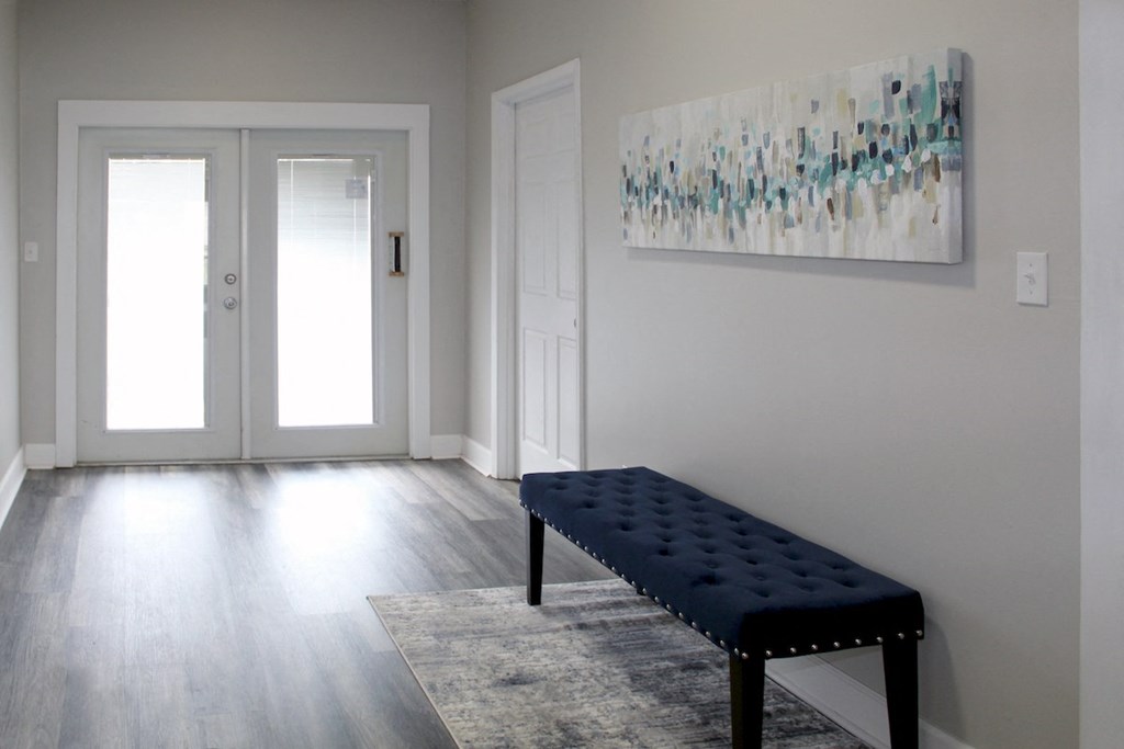 Clubhouse entrance hall with a padded bench and artwork at Woodland Villas Apartments, Jasper, AL 35504