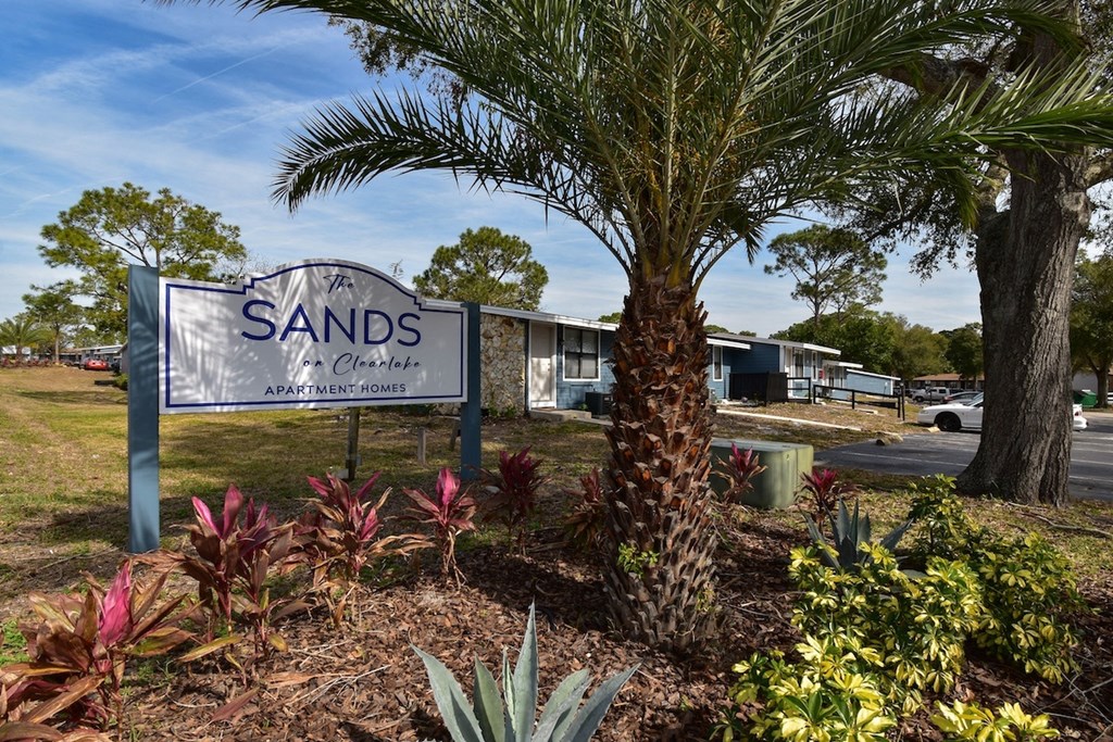 The monument sign for The Sands on Clearlake surrounded by lush landscaping and palm trees