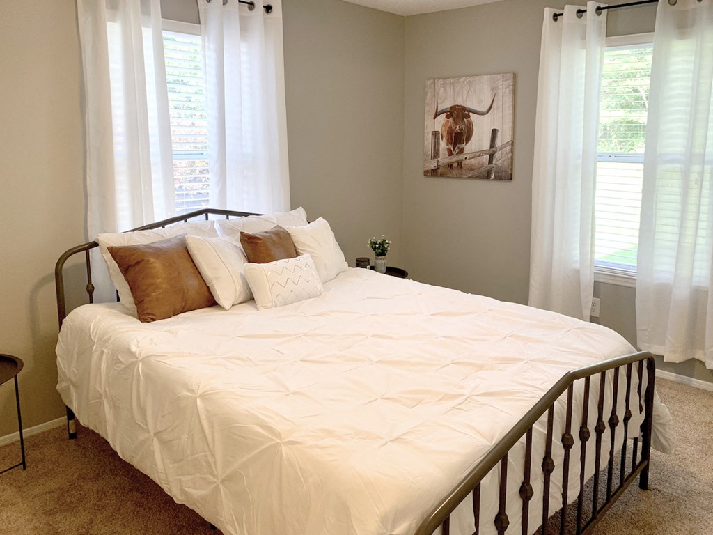 a bedroom with 2 large windows and model bed and decor
