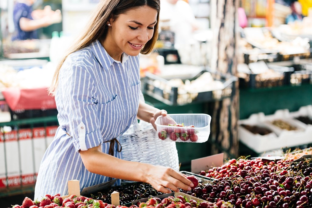 A woman is shopping for grapes at a market.