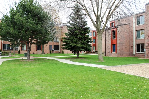 A grassy area in front of a building with trees.