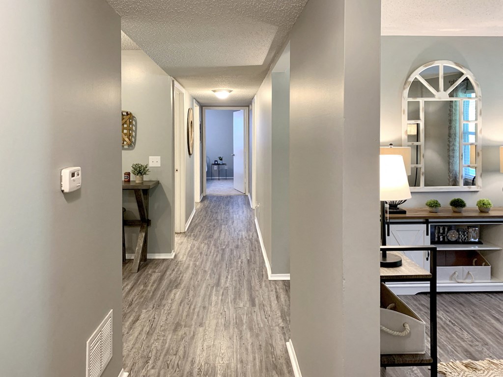 a hallway with grey walls, wood-style floor, and white trim