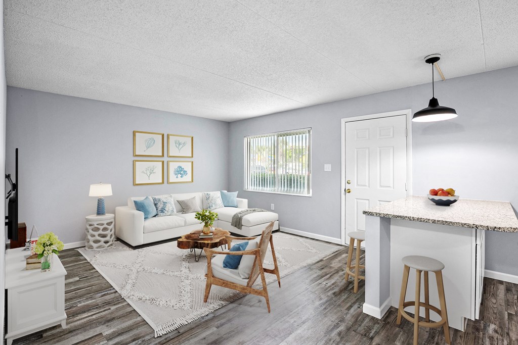 A living room with a white couch, a coffee table, and a dining table.