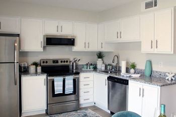 a kitchen with white cabinets and stainless steel appliances  at Huntsville Landing Apartments, Alabama