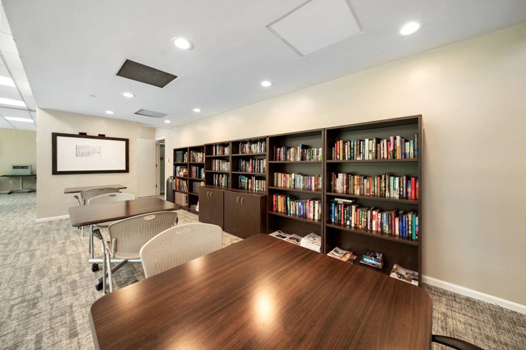 a conference room with a table and chairs and a library filled with books