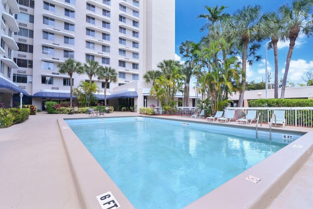 a large swimming pool in front of a hotel with palm trees