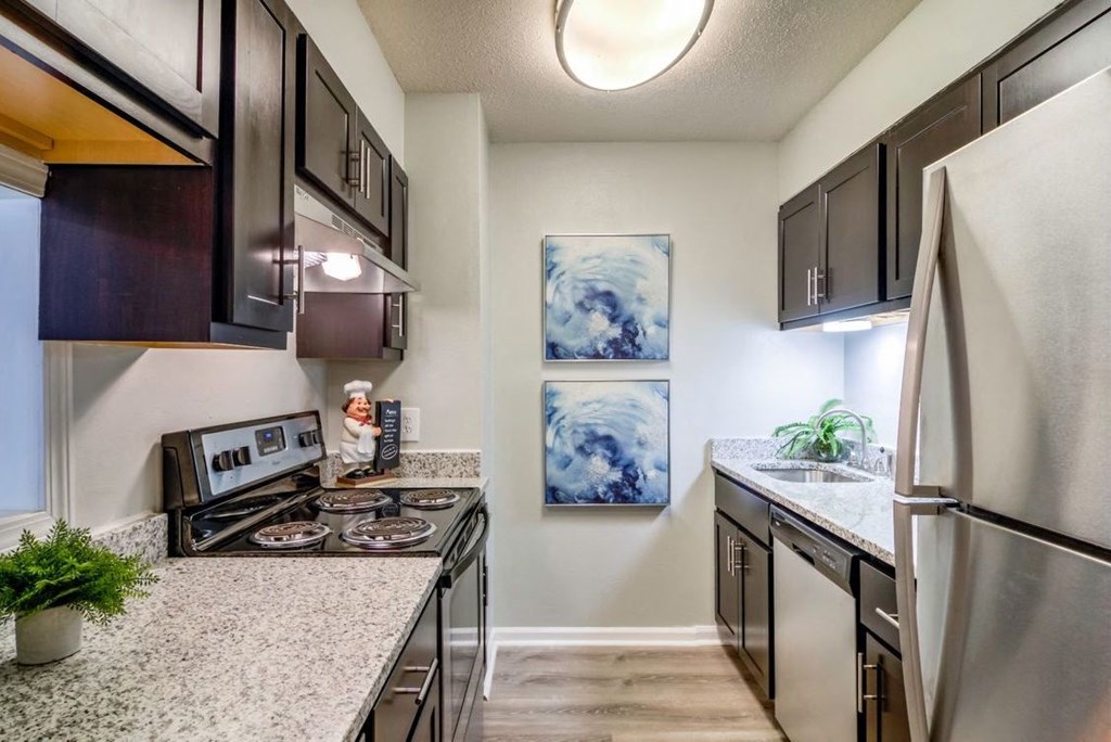 Galley-style kitchen with stainless steel appliances, granite countertops, and ample cabinetry