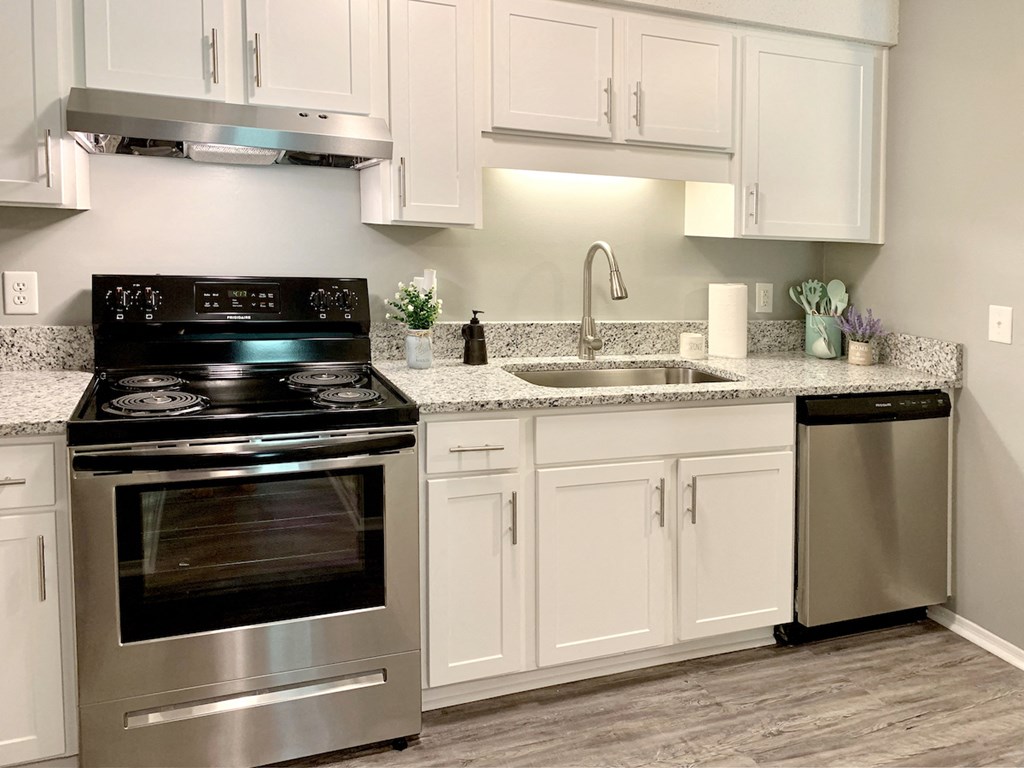 stainless steel appliances, wood style floors, and white cabinets in kitchen