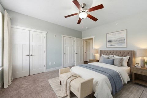 A bedroom with a large bed and a ceiling fan.