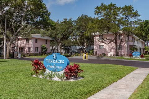 Monument signs with tropical plants, mature trees, and well-kept apartment buildings at Terraces at Clearwater Beach, Florida, 33756