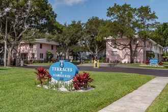 Monument signs with tropical plants, mature trees, and well-kept apartment buildings at Terraces at Clearwater Beach, Florida, 33756 - Photo Gallery 1