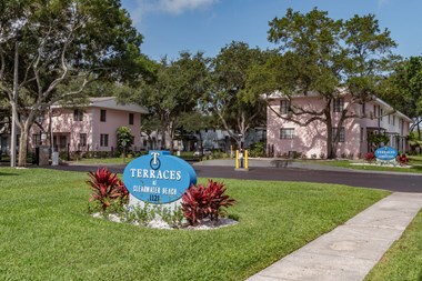 Monument signs with tropical plants, mature trees, and well-kept apartment buildings at Terraces at Clearwater Beach, Florida, 33756