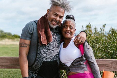 a man and woman in work out clothing standing outside and smiling