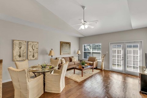 A well-lit living room with a glass table and chairs.