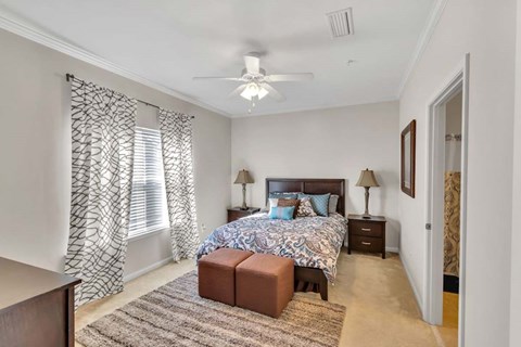 A bedroom with a patterned bedspread and a ceiling fan.