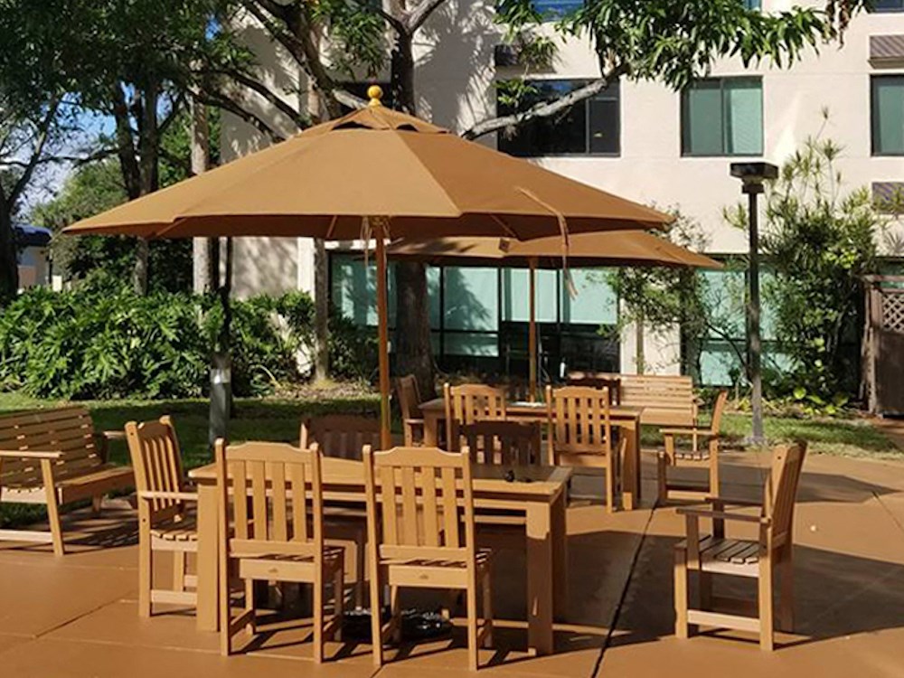 large tables with umbrellas outside at B'nai B'rith I, II, III deerfield apartments in deerfield beach, FL