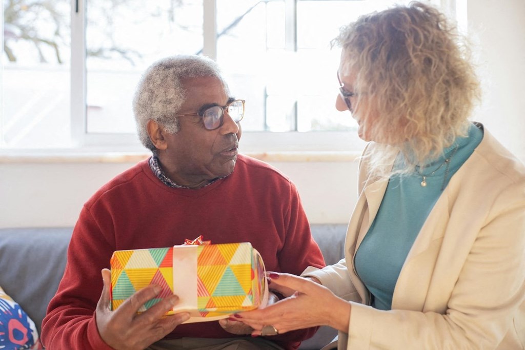 a woman giving a gift to an older man