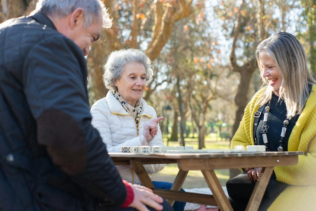 a group of people sitting outside at a table playing chess