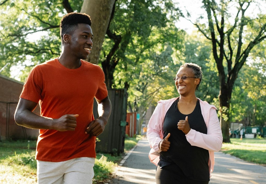 a young man and an older woman jogging down a sidewalk