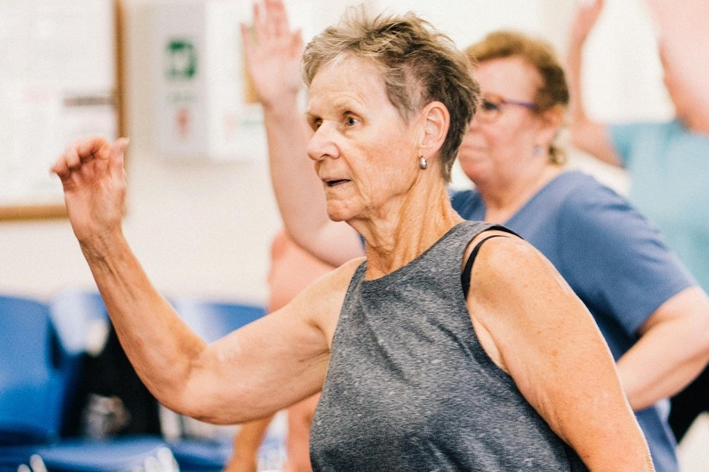 several older woman in an excercise class with thier arms in the air