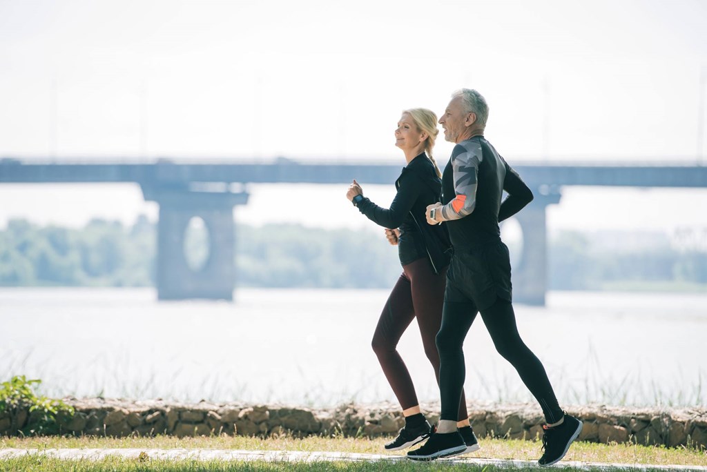 Two people jogging in front of a bridge.