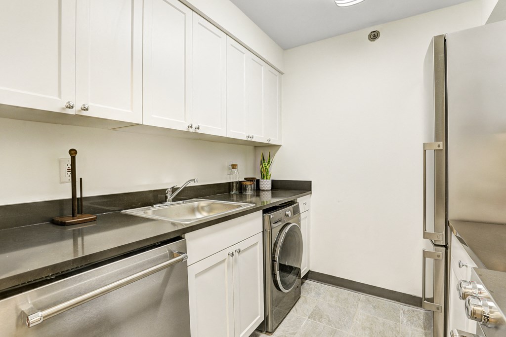 a kitchen with white cabinets and stainless steel appliances and a sink