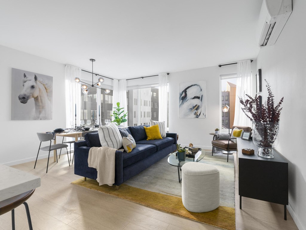 a living room with white walls and a blue couch with yellow and white pillows