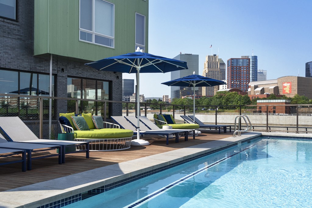 a pool with lounge chairs and umbrellas in front of a building