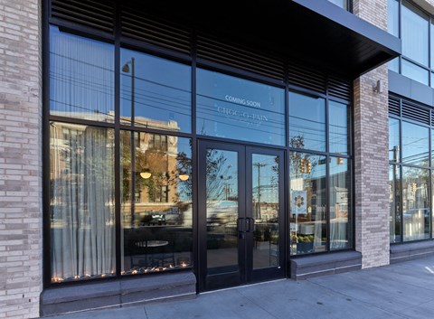 the front of a building with glass doors and a sidewalk