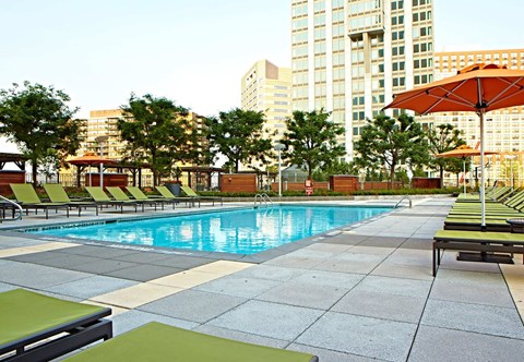 a swimming pool with chaise lounge chairs and umbrellas in front of a large building