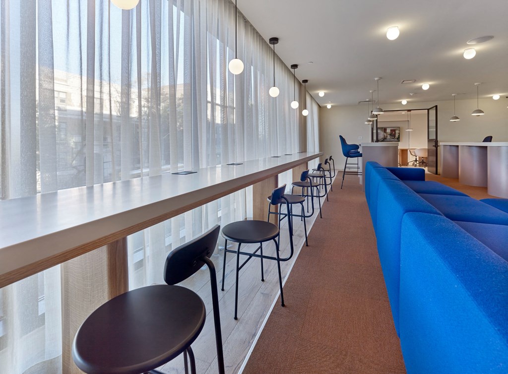 a row of blue chairs and tables in a room with windows