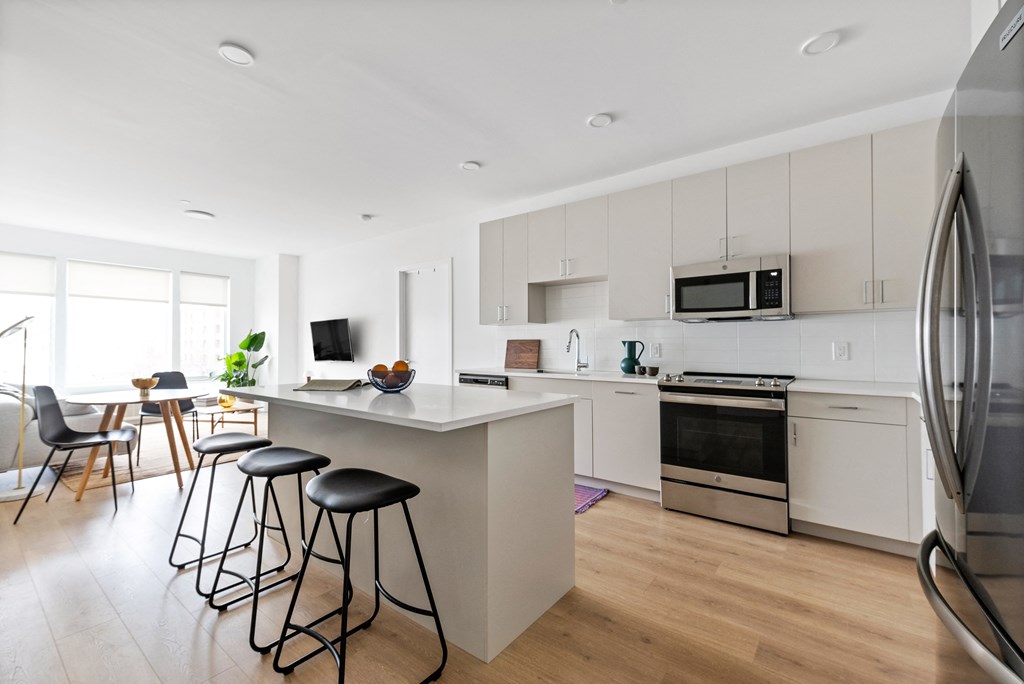 a kitchen with white cabinets and a large island with three stools
