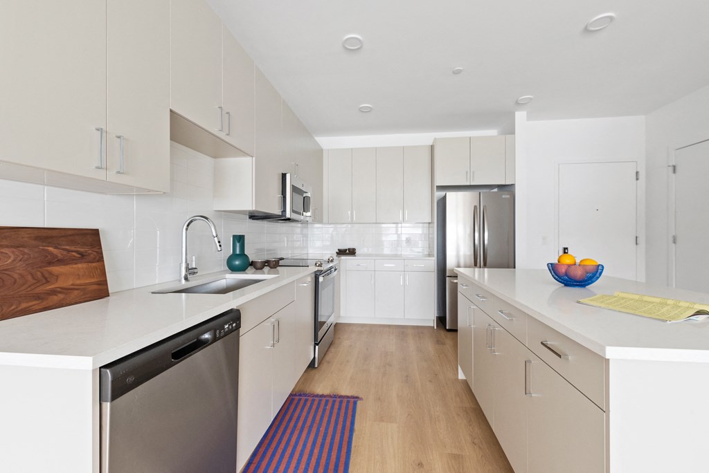 a white kitchen with stainless steel appliances and white counter tops