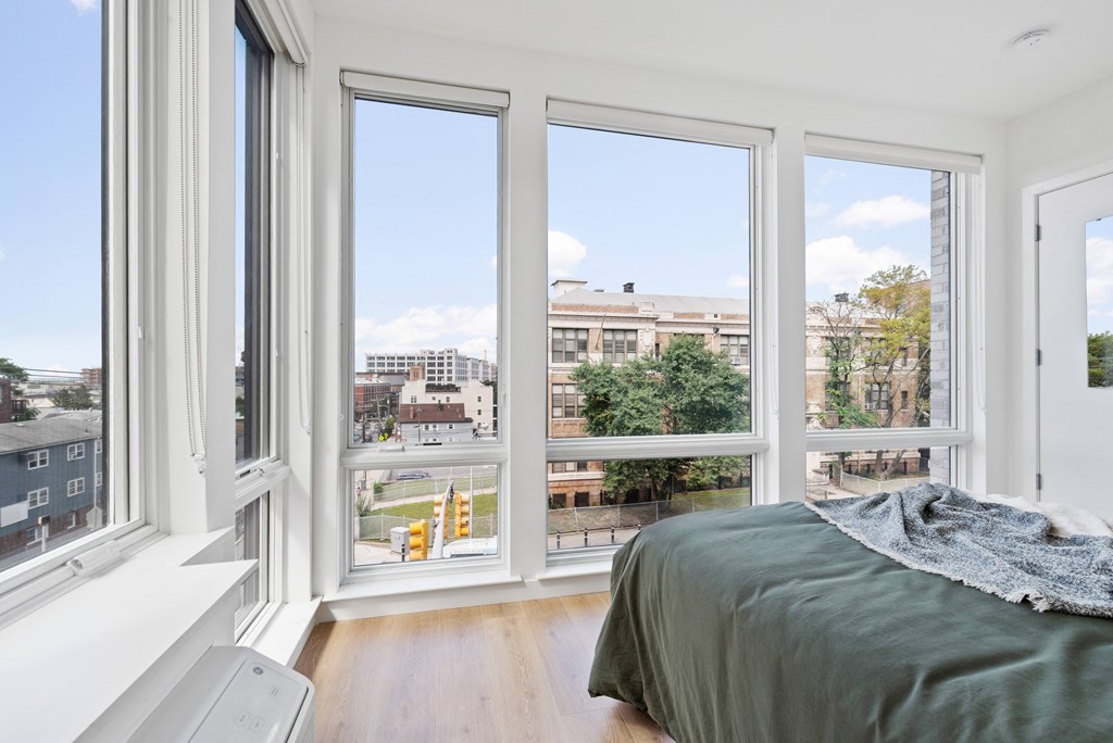 a bedroom with four windows and a bed and a city view