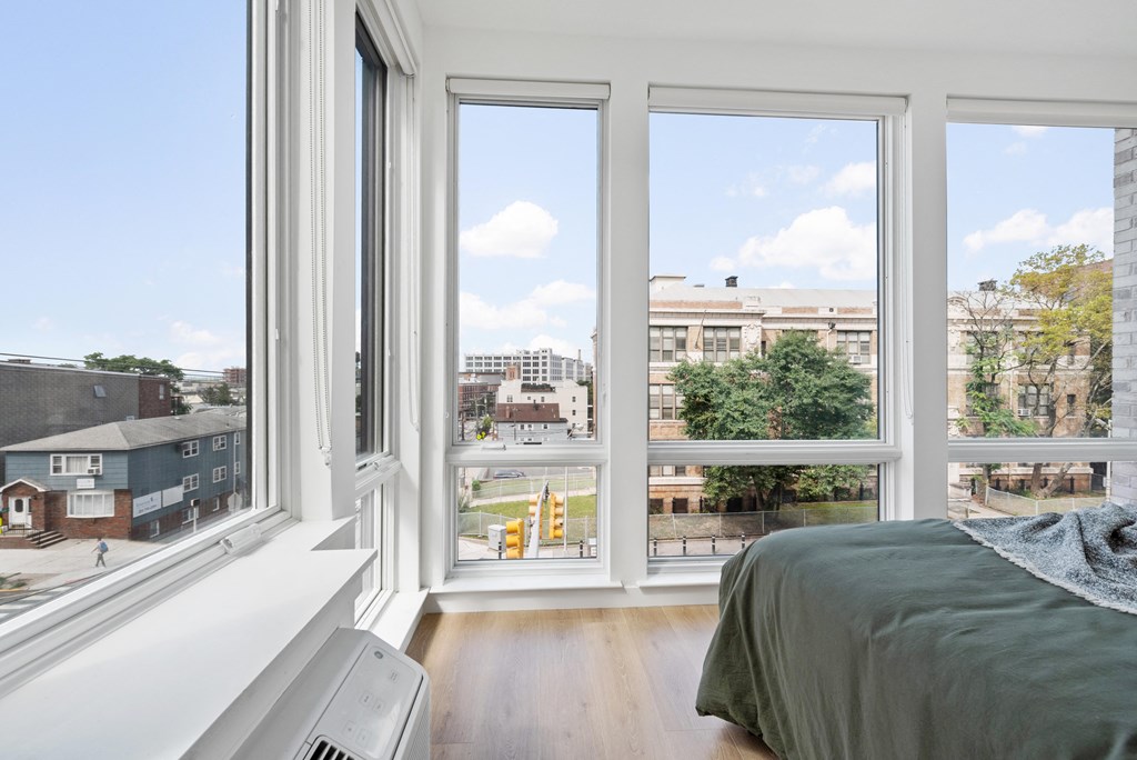 a bedroom with large windows and a bed and a city view