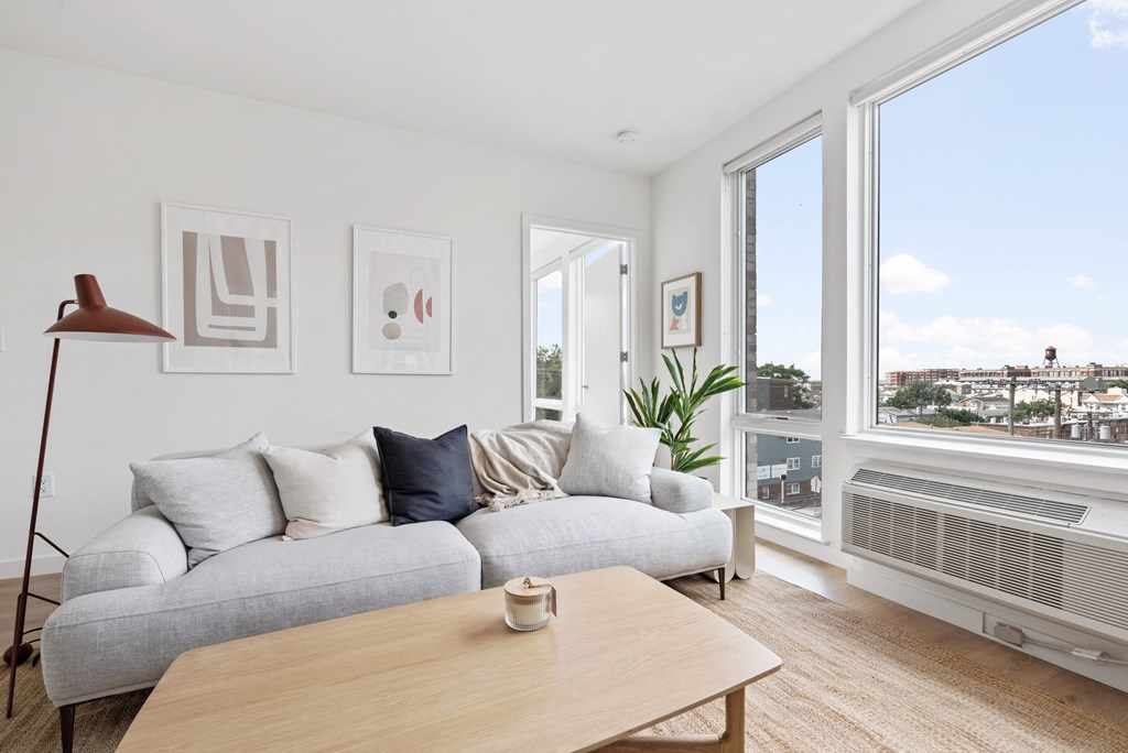 a living room with a couch and a coffee table and large windows