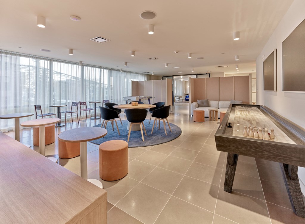 a common room with tables and chairs and a shuffleboard