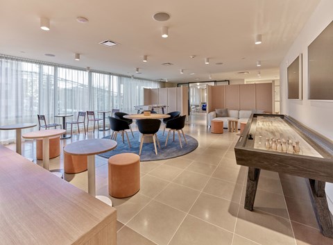 a common room with tables and chairs and a shuffleboard