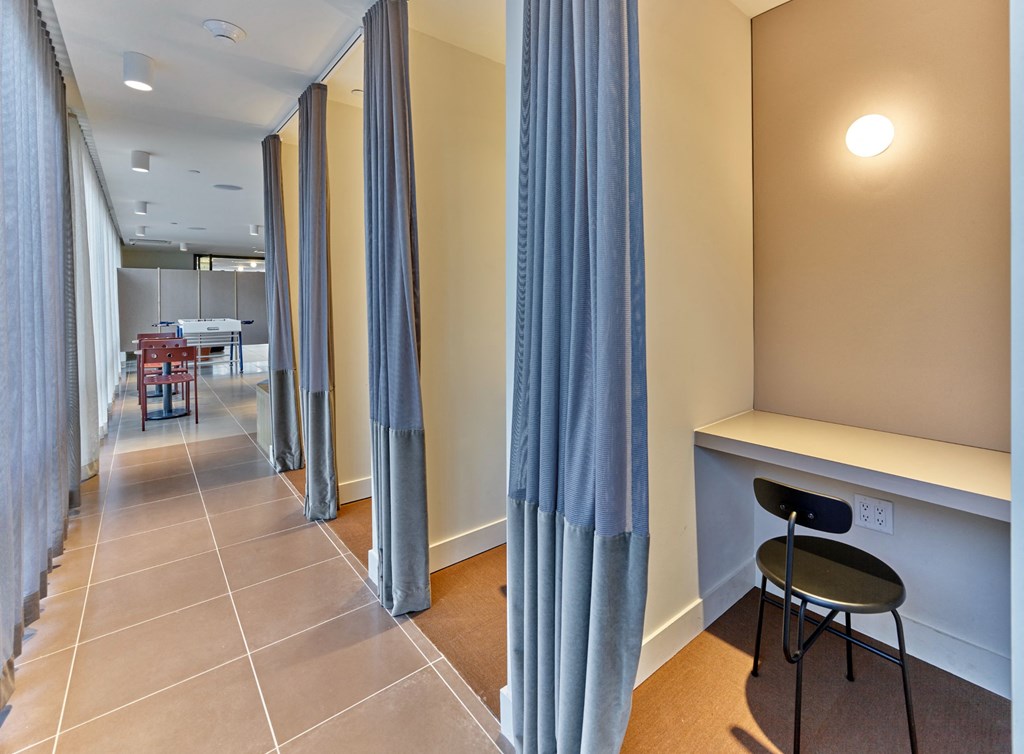 a corridor with blue curtains and a table and chairs in a hotel room
