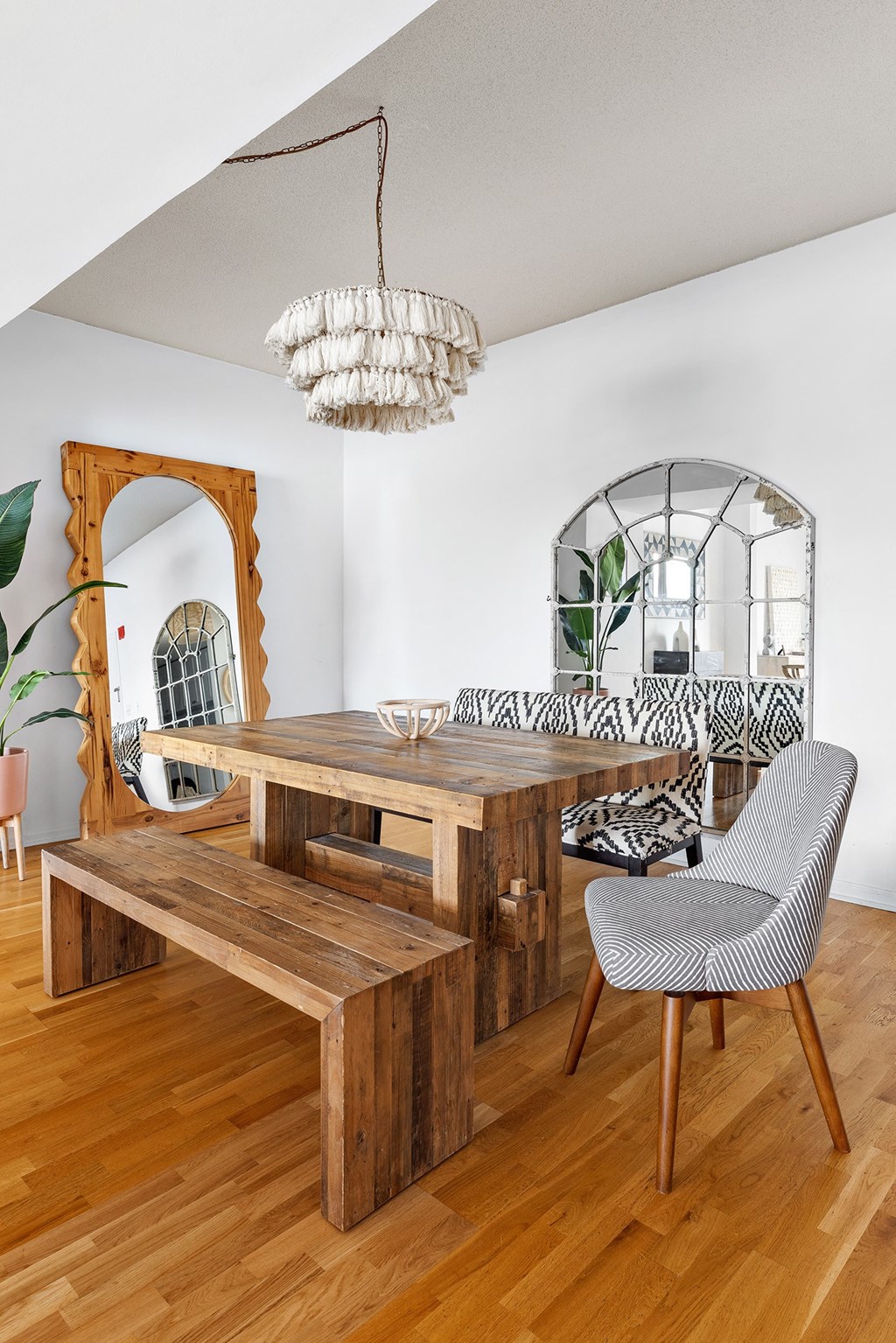 a dining room with a wooden table and bench and a chandelier
