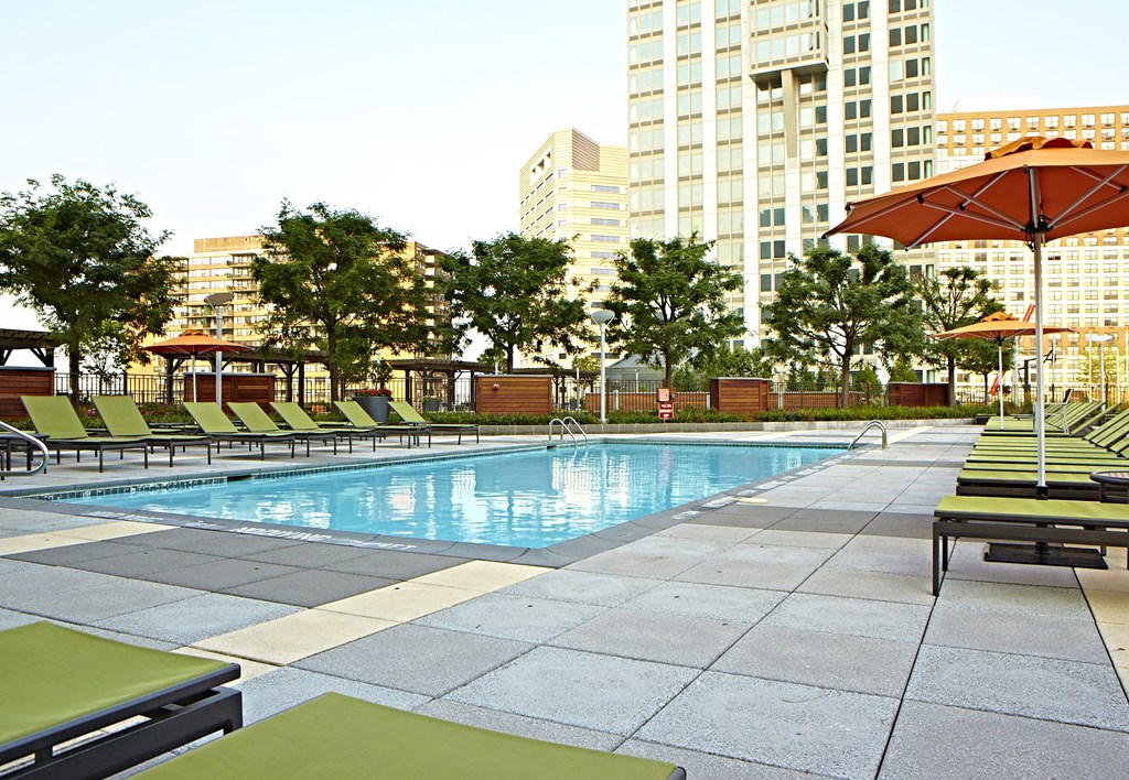 a swimming pool with chaise lounge chairs and umbrellas in front of a large building