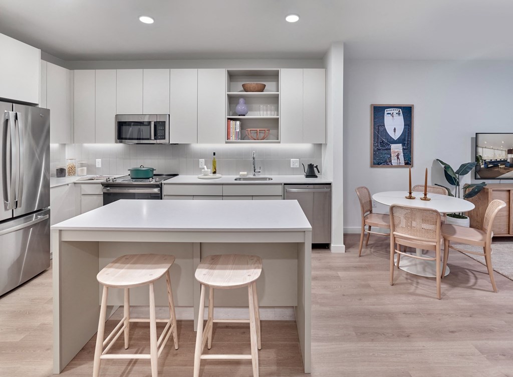 a kitchen with an island with three stools and a dining table