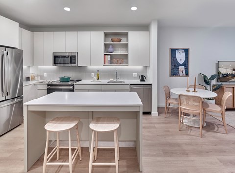 a kitchen with an island with three stools and a dining table