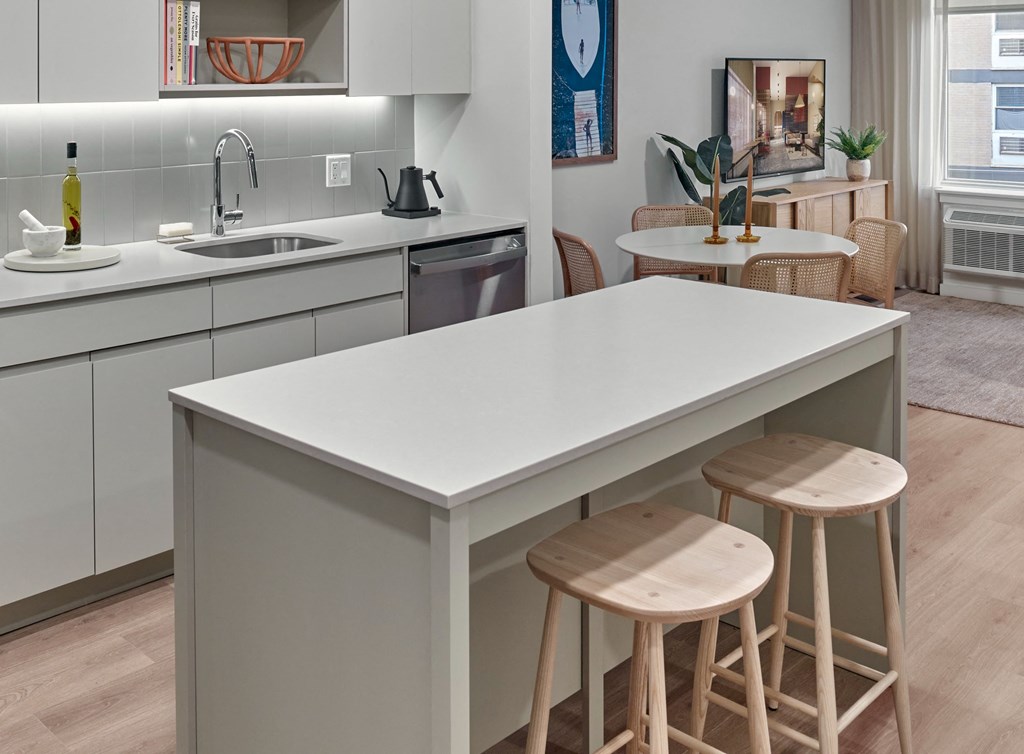 a kitchen with a white counter top and three stools